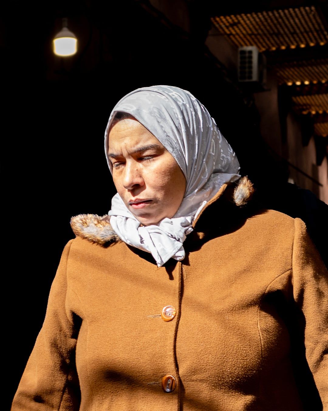 A woman in an orange coat and headscarf