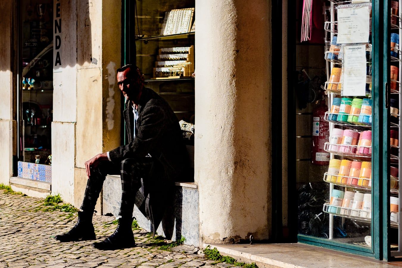 A man sitting outside a colourful shop